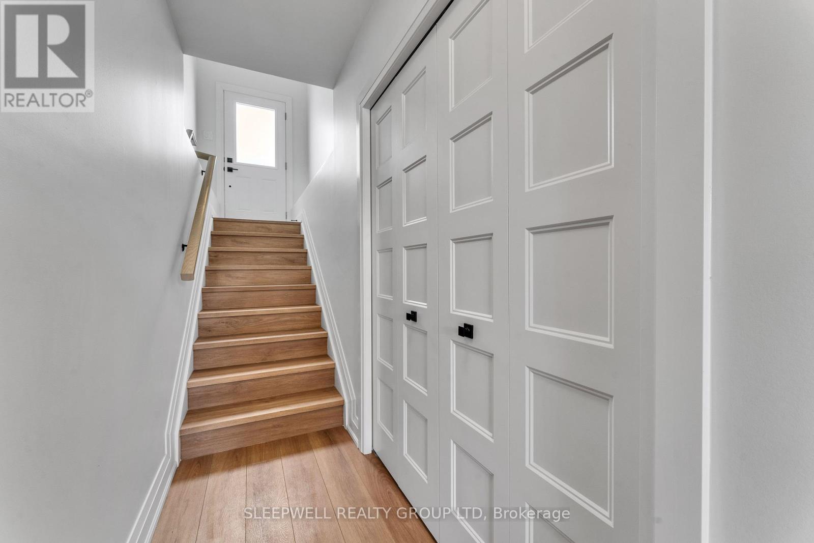A hallway with a staircase and a white door.