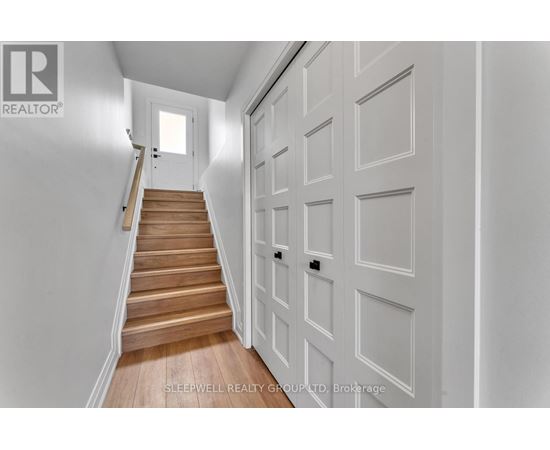 A hallway with a staircase and a white door.