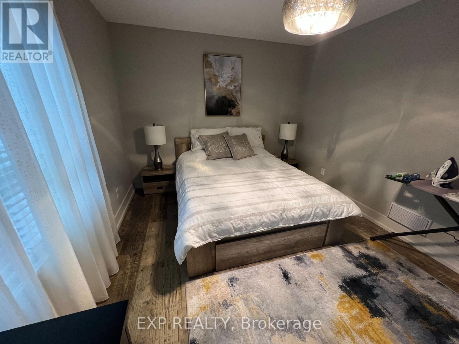 A bedroom with a large bed and a painting on the wall.