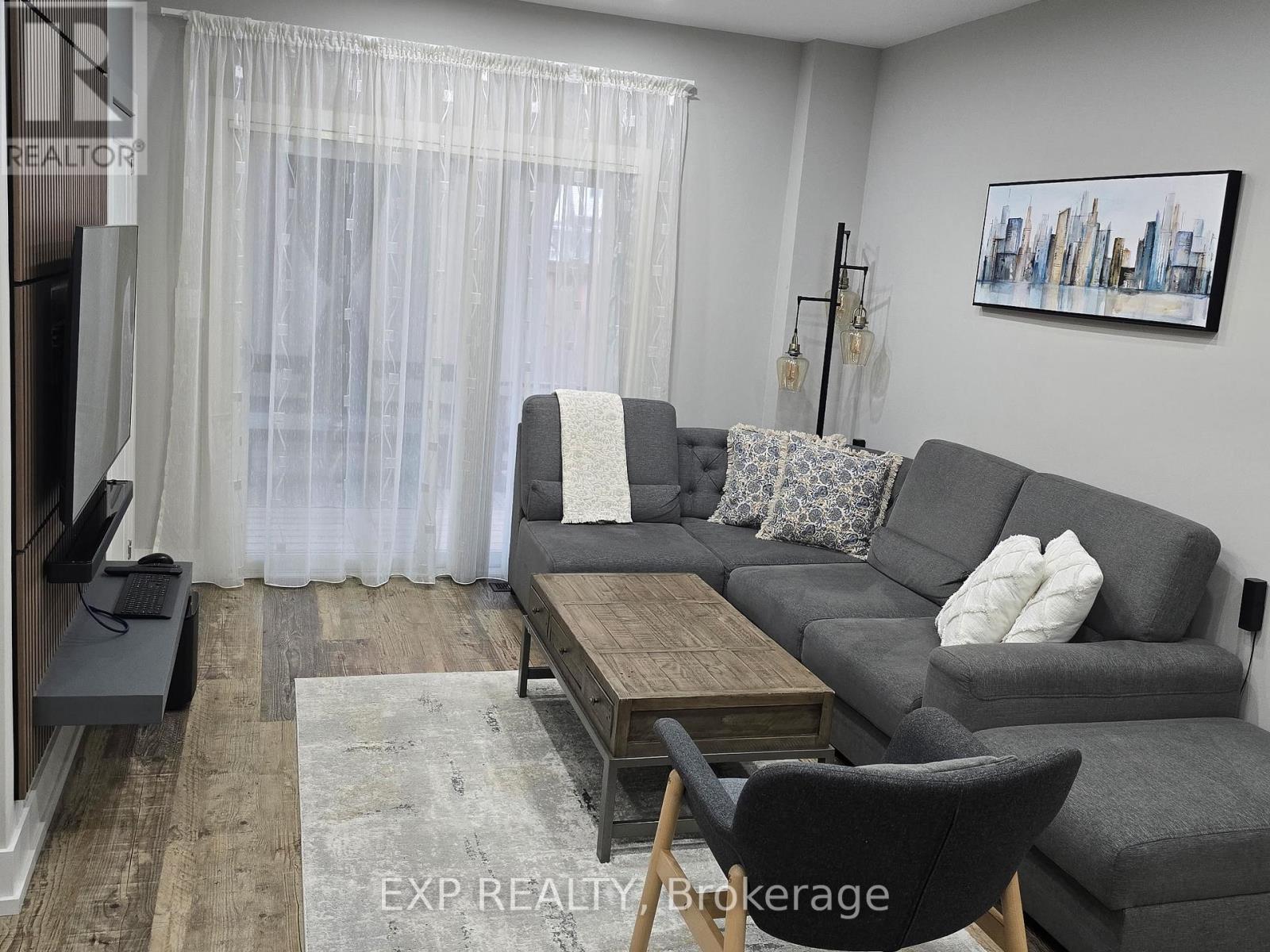 A living room with a grey couch, a wooden coffee table, and a painting on the wall.
