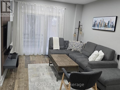 A living room with a grey couch, a wooden coffee table, and a painting on the wall.