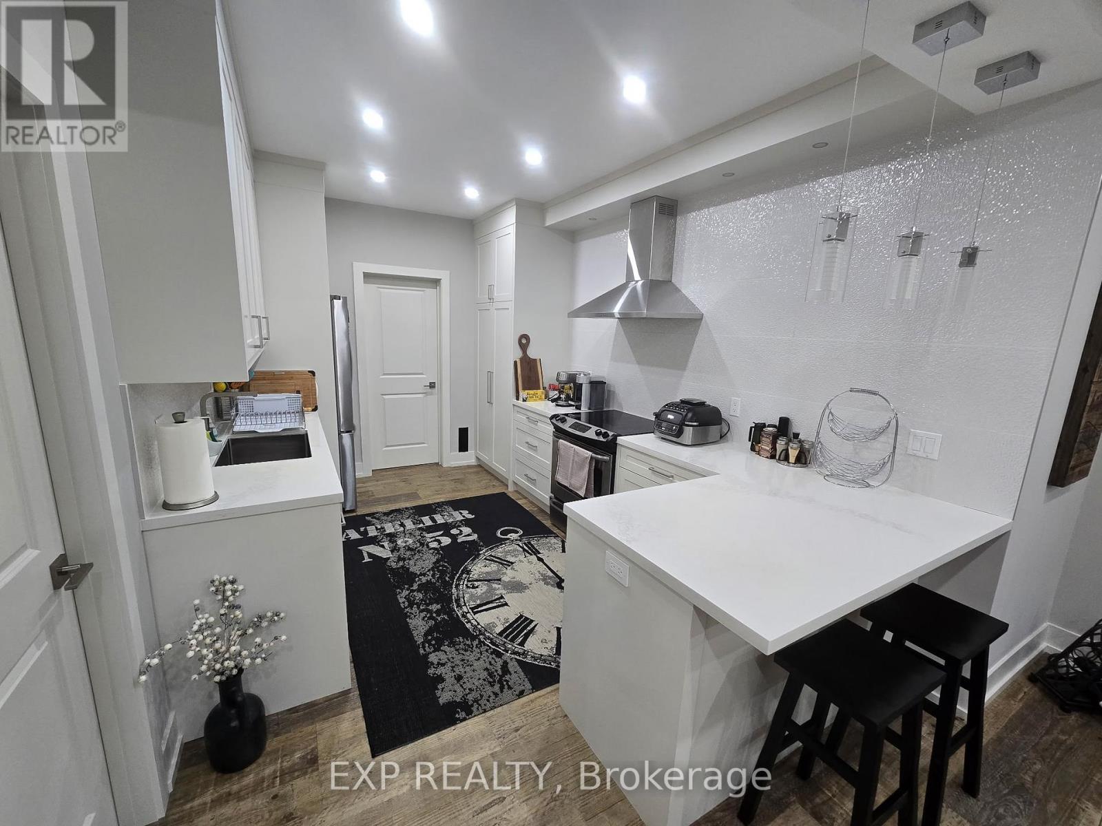 A kitchen with a white counter top and a black and white rug on the floor.