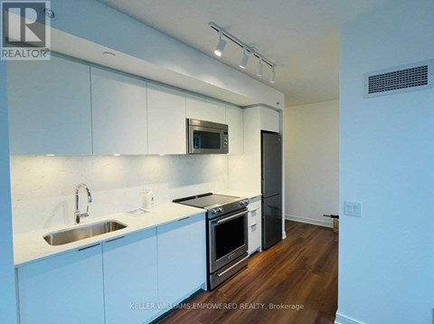 A modern kitchen with white cabinets and stainless steel appliances.