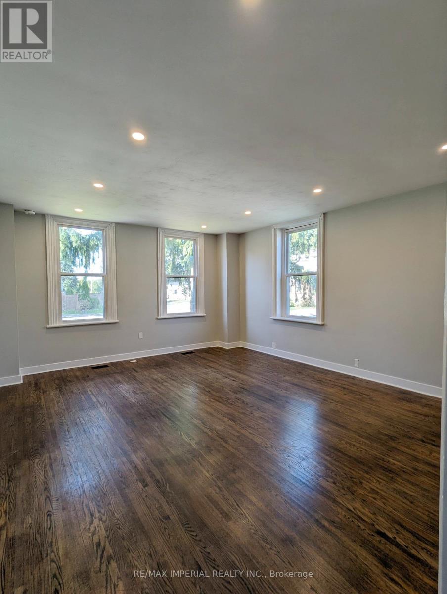 A room with wooden floors and three windows.