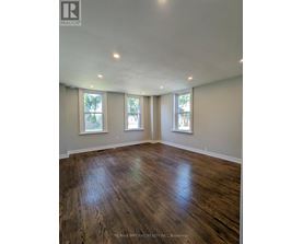 A room with wooden floors and three windows.