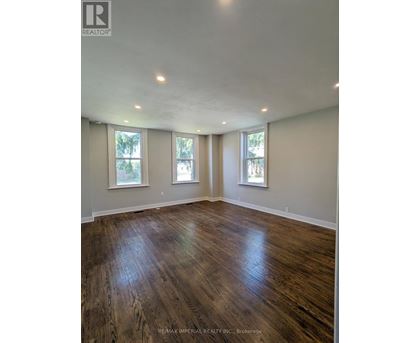 A room with wooden floors and three windows.