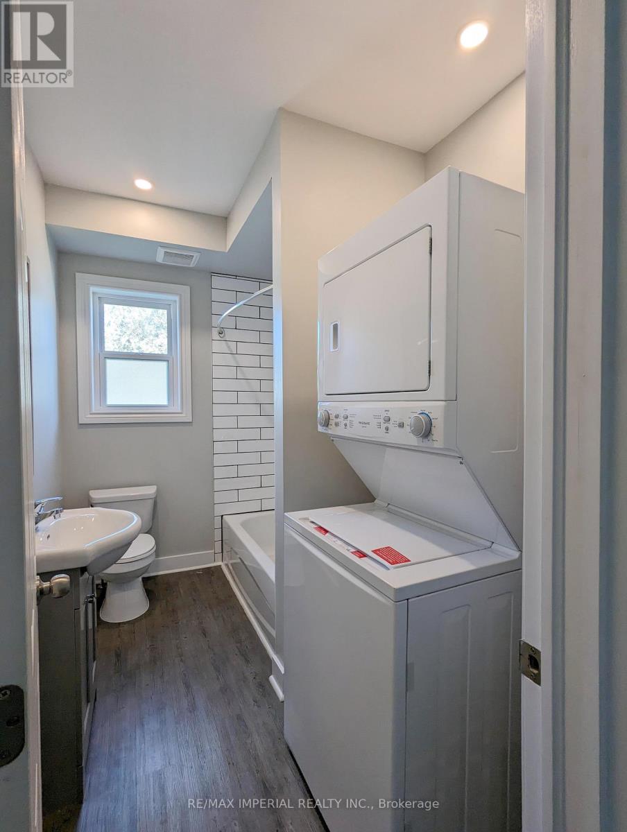 A bathroom with a toilet, sink, and a window.