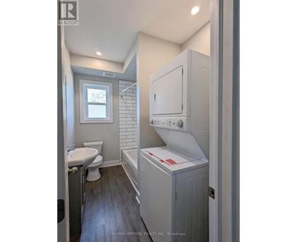 A bathroom with a toilet, sink, and a window.