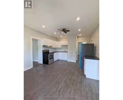 A kitchen with white cabinets and a black fridge.