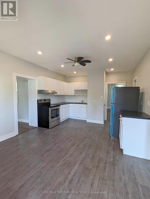A kitchen with white cabinets and a black fridge.