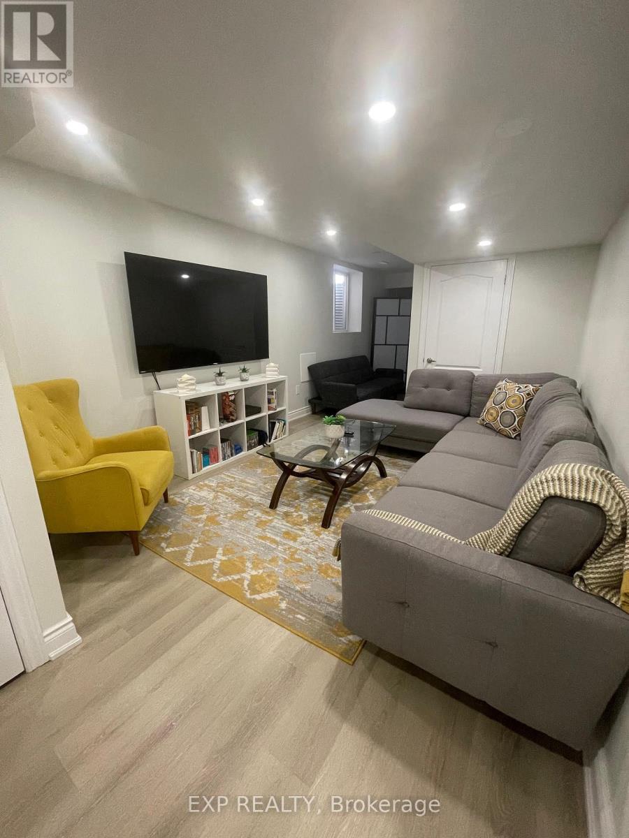 A living room with a grey couch, a yellow chair, and a flat screen TV mounted on the wall.