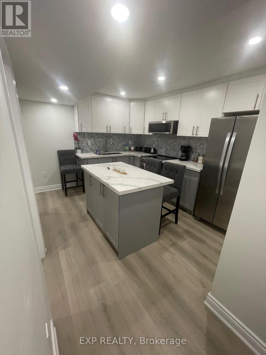 A kitchen with a refrigerator, microwave, and a counter with a sink.
