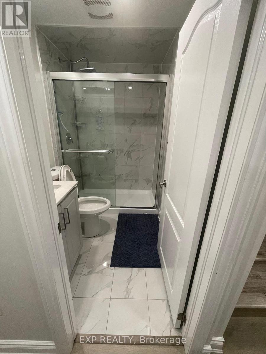 A bathroom with a glass shower door and a toilet.