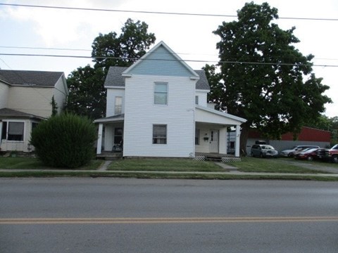A white house with a blue roof is situated on a street.