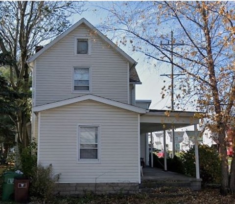 A two-story house with a porch and a covered entryway.