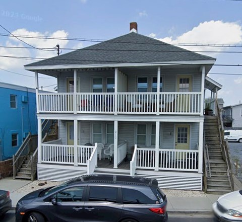 A house with a blue building next to it and a car in front.