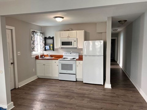 A kitchen with white appliances and wooden floors.