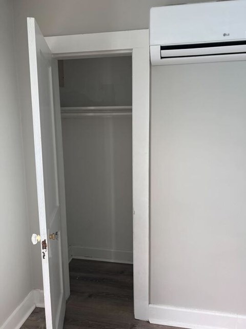 A white door is open to a room with a wall-mounted air conditioner.