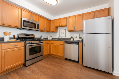 A kitchen with wooden cabinets and a stainless steel refrigerator.