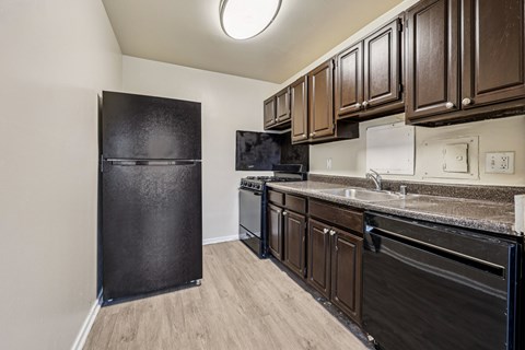 A kitchen with black appliances and brown cabinets.