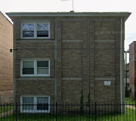A brick building with a black fence in front.