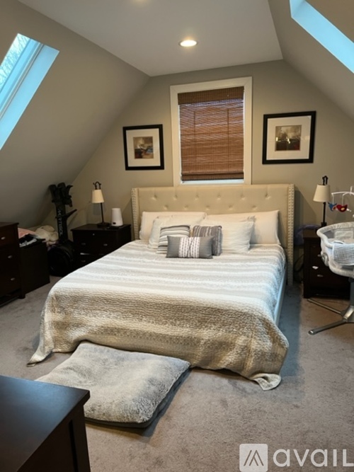 A bedroom with a large bed and a window with blinds.