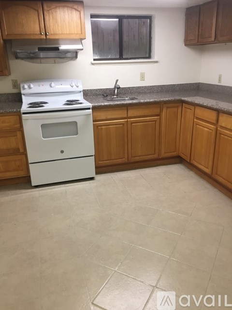 A kitchen with a white stove and wooden cabinets.