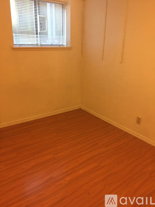 A room with wooden flooring and a window with blinds.