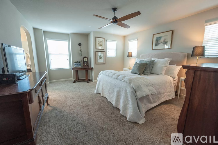 A bedroom with a bed, dresser, and ceiling fan.