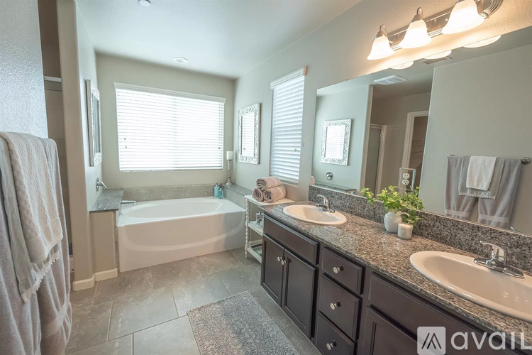 A bathroom with a tub, sink, and mirror.
