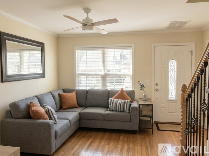 A living room with a grey couch and a ceiling fan.