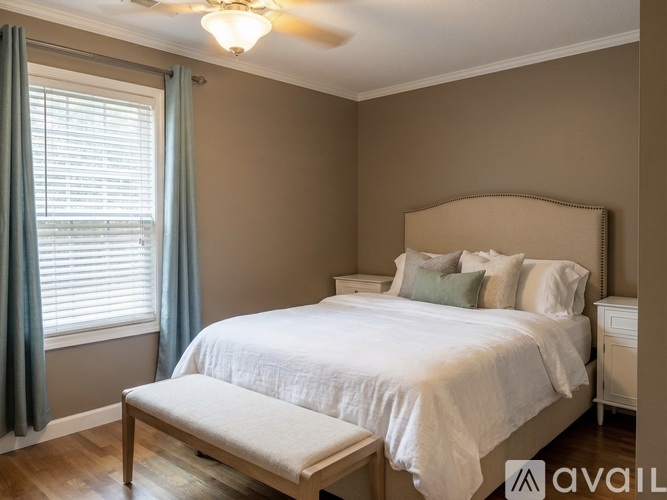A bedroom with a bed, nightstand, and window with curtains.