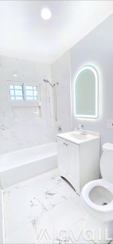 A white bathroom with a marble floor and a round mirror.