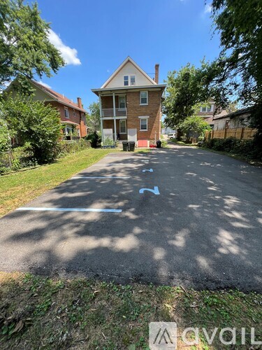 A residential street with houses on both sides and a blue arrow painted on the road.