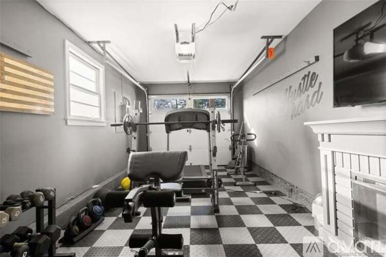 A black and white checkered floor in a gym with a weight bench and dumbbells.