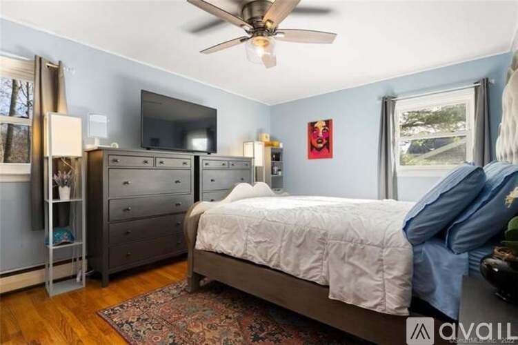 A bedroom with a bed, dresser, and television.