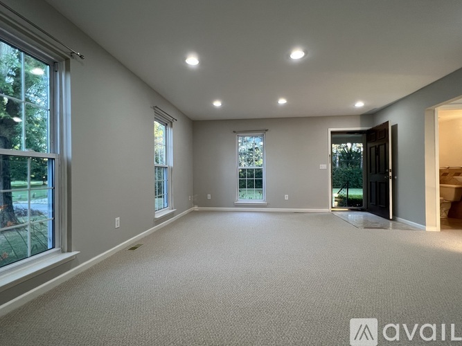 A spacious room with large windows and carpeted floor.