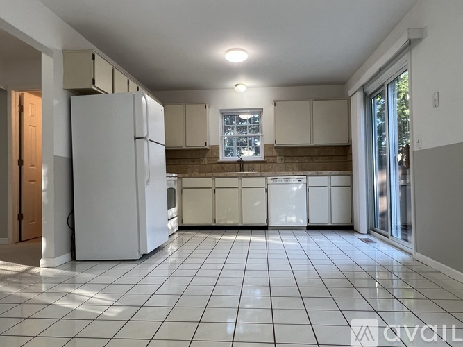 A kitchen with white appliances and a tiled floor.