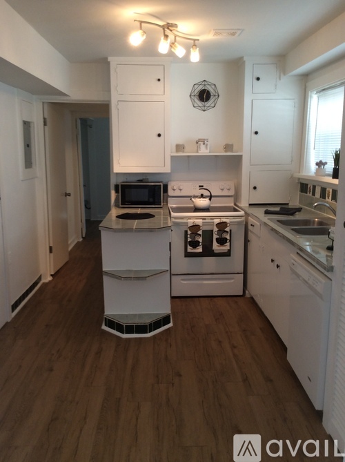 A kitchen with white appliances and wooden floors.
