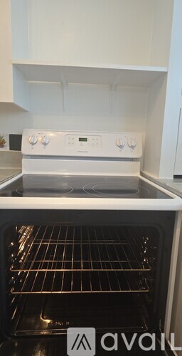 A white oven with four knobs and a digital display is in a kitchen.
