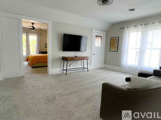 A living room with a television, a couch, and a fan.