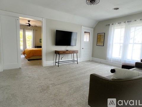A living room with a television, a couch, and a fan.