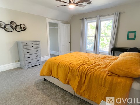A bedroom with a bed, dresser, and ceiling fan.