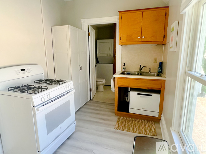 A small kitchen with a white stove and wooden cabinets.