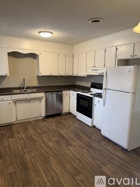 A kitchen with white appliances and wooden floors.