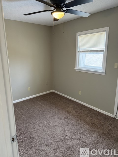A room with a ceiling fan and a window.