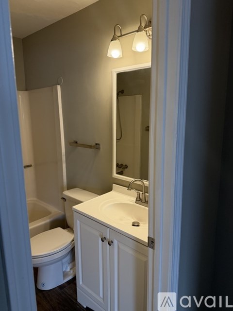 A bathroom with a toilet, sink, and mirror.