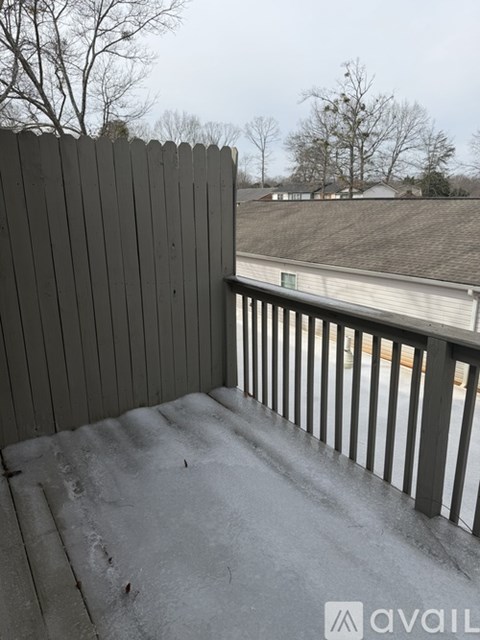 A balcony with a wooden railing and a grey wall.