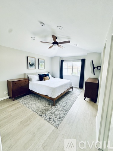 A bedroom with a bed, nightstand, and a ceiling fan.