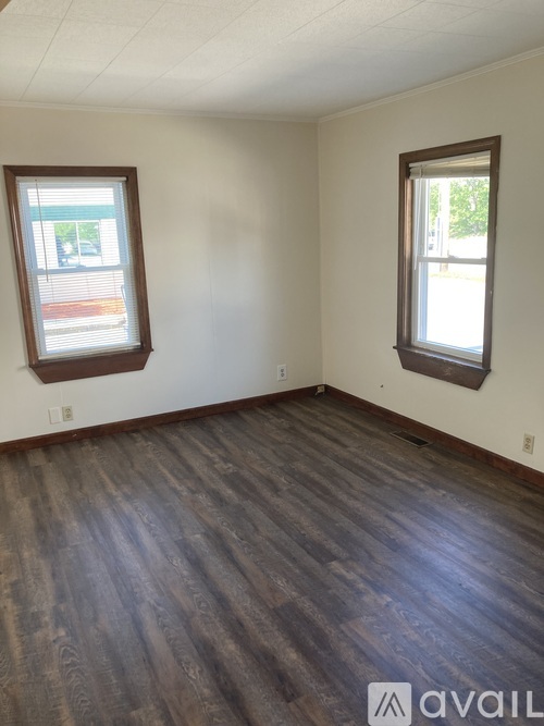 A room with wooden floors and two windows.